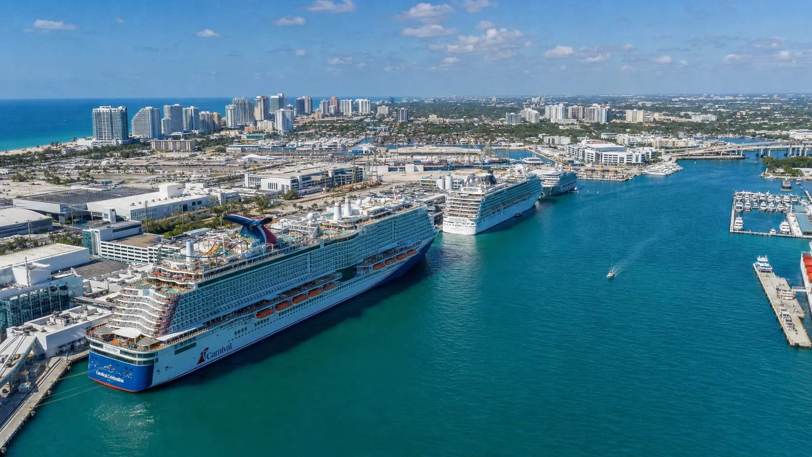 Aerial view of Port Everglades in Fort Lauderdale with massive cruise ships docked at terminals and the Fort Lauderdale skyline and beach in the background